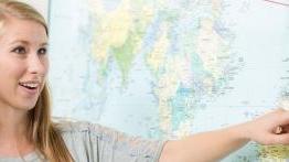 Female student points at wall-sized international map.