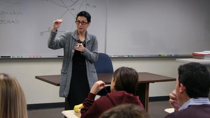 Maria Pia Paganelli stands at front of classroom, 手持干擦记号笔, 在白板前教学生