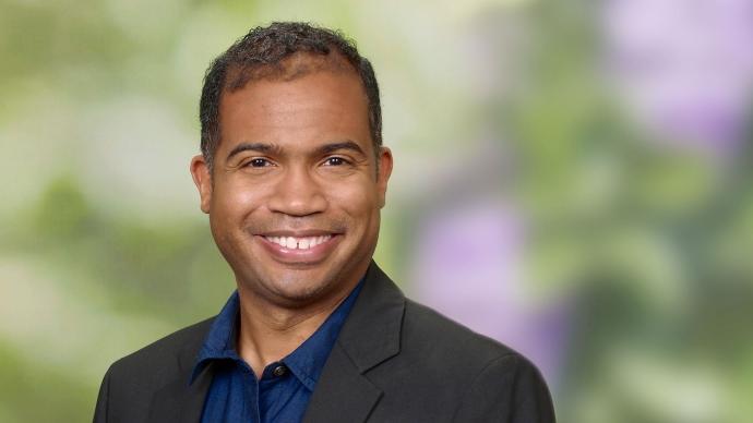 headshot of Carey Latimore against a purple and green background