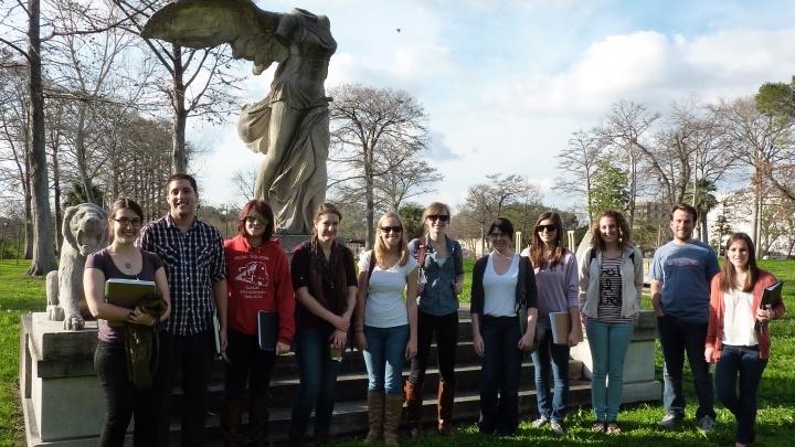 学生 gather outside for a group photo in front of a winged statue